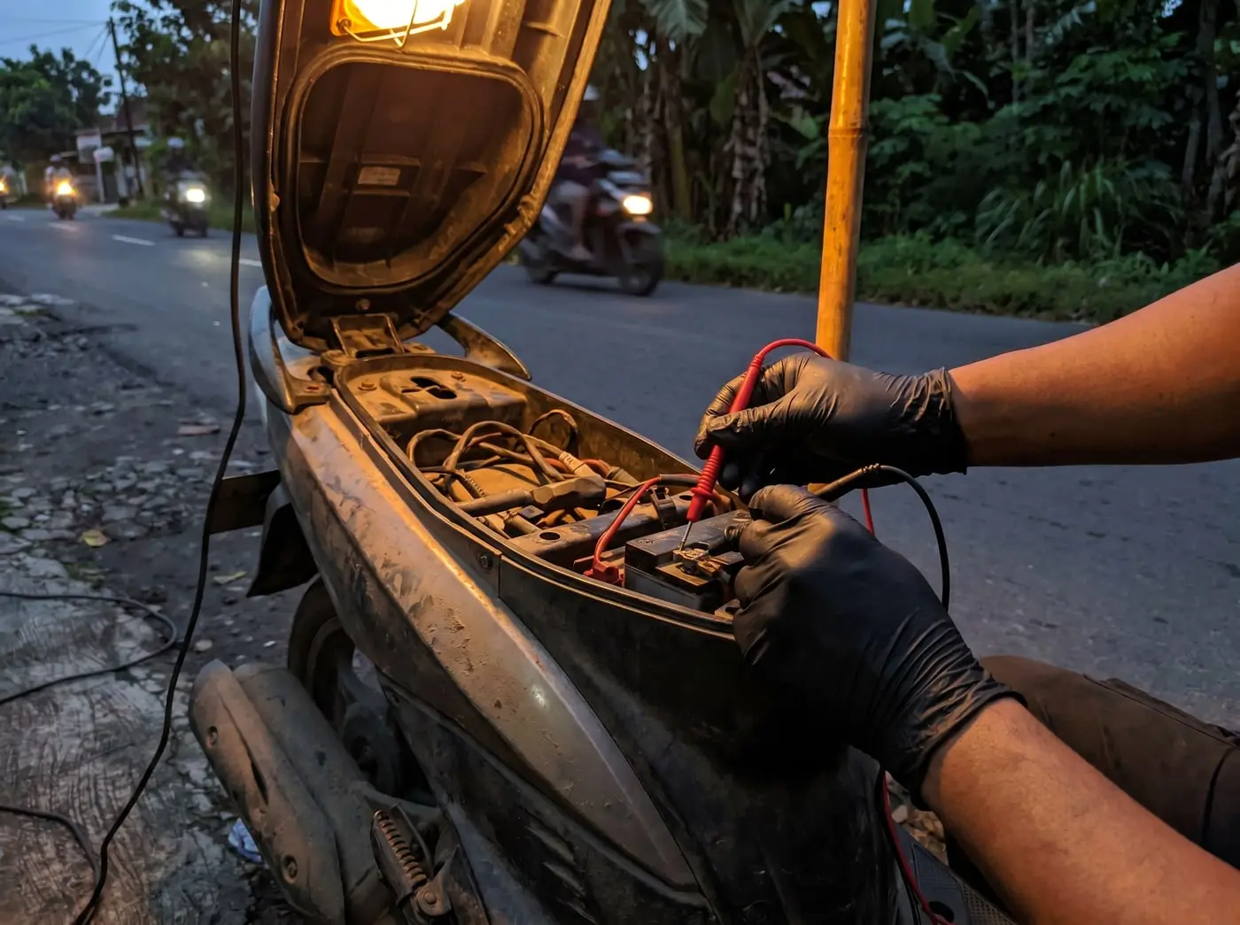 Mekanik MotoCall mengecek aki motor dengan multimeter sebelum menjelaskan biaya ke pelanggan