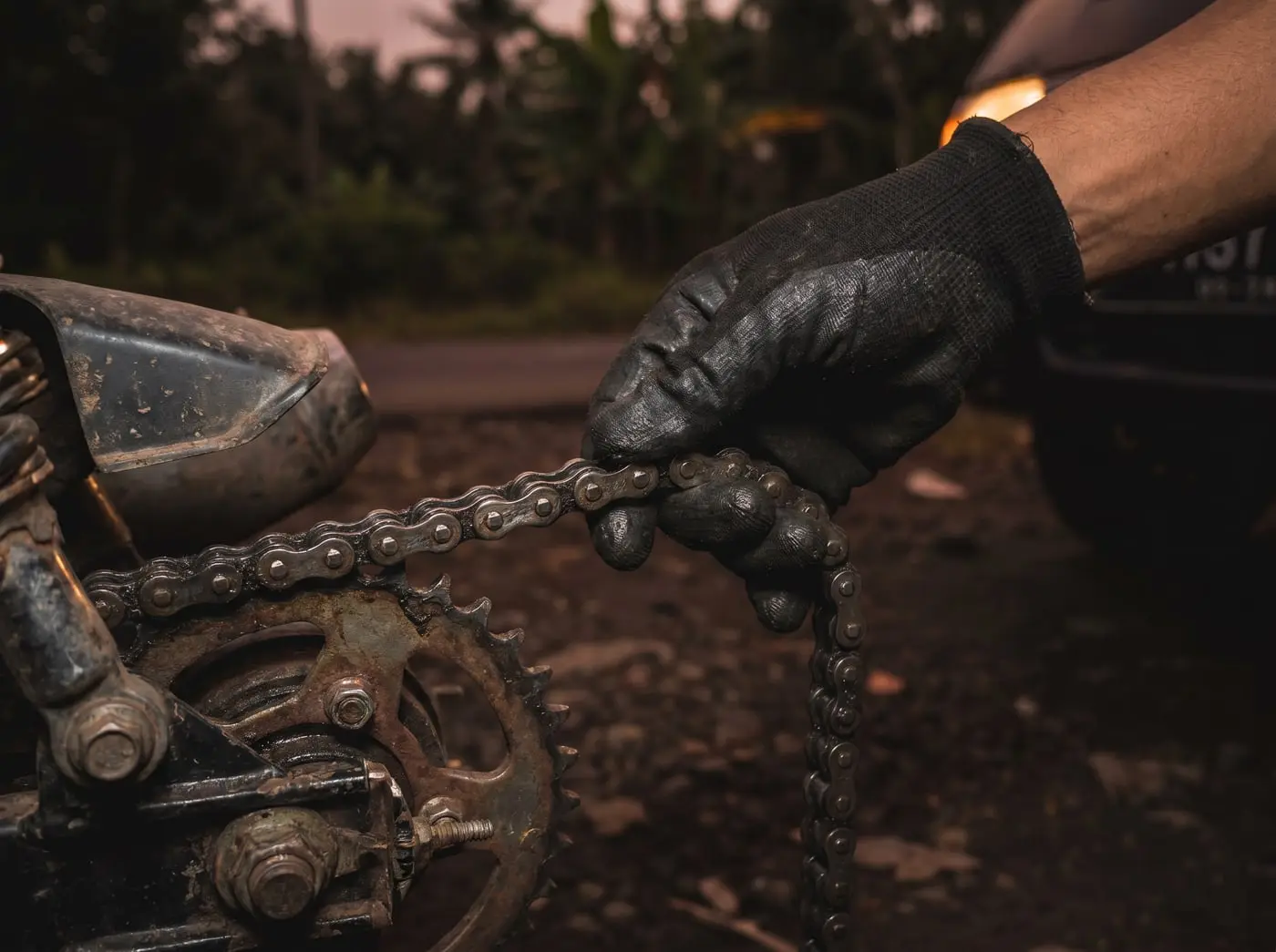 Montir MotoCall memeriksa dan melumasi rantai motor yang bunyi kasar di lokasi pelanggan