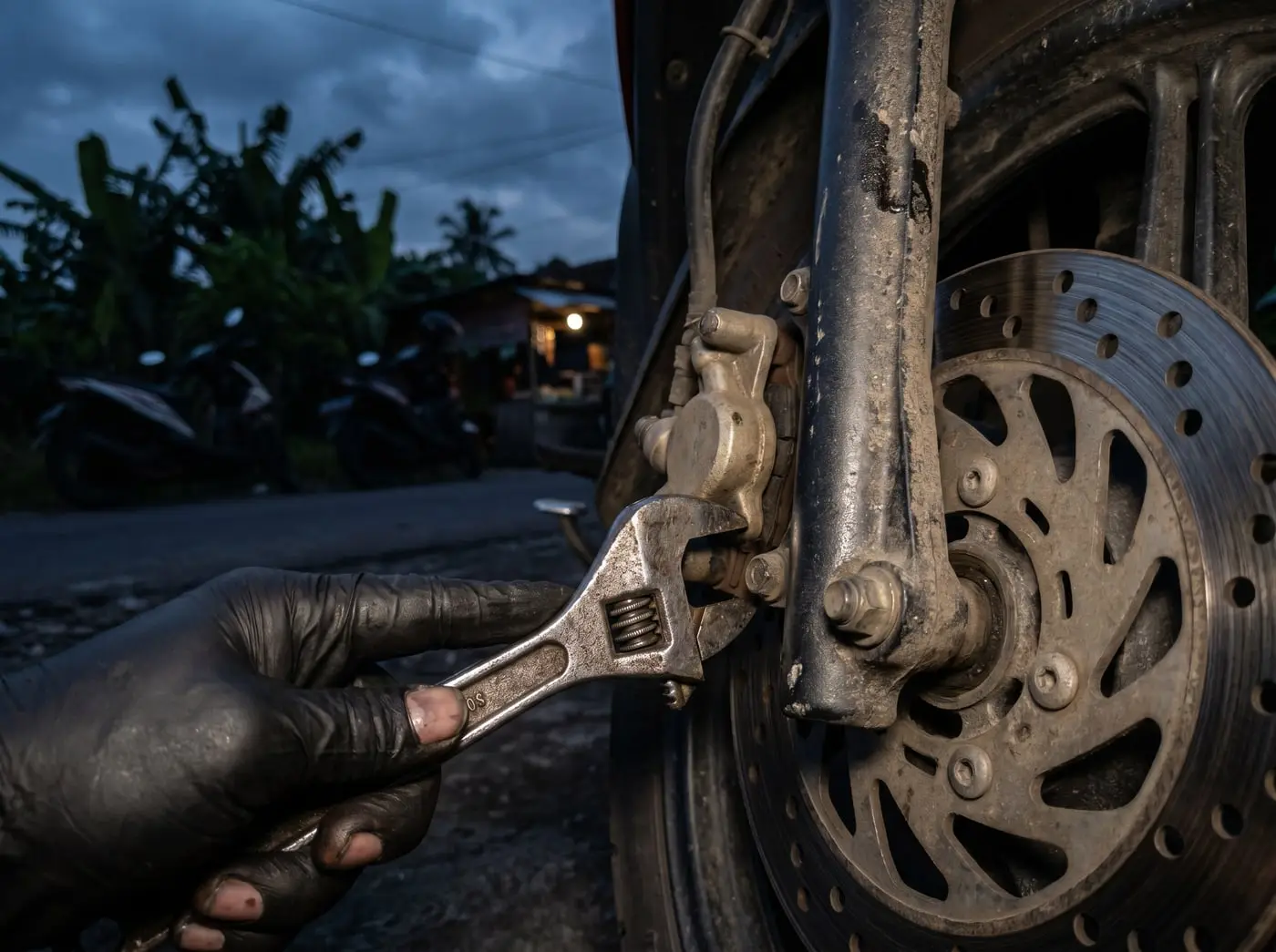Mekanik memeriksa kaliper rem cakram depan motor di pinggir jalan